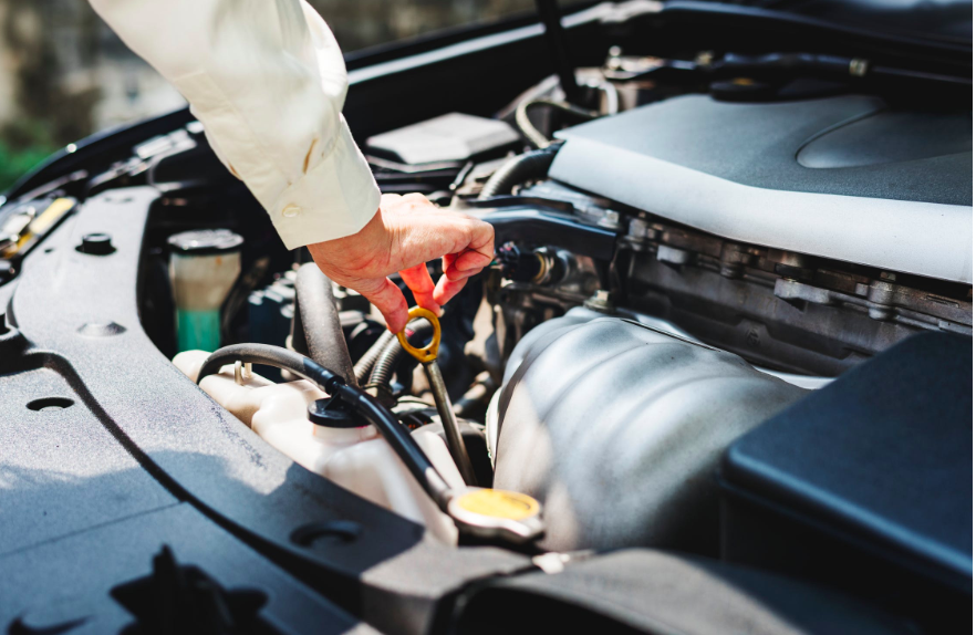 guide to car maintenance: person touching gray metal rod on vehicle engine