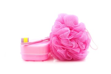 pink toothbrush, soapbox and shower scrubber on white background